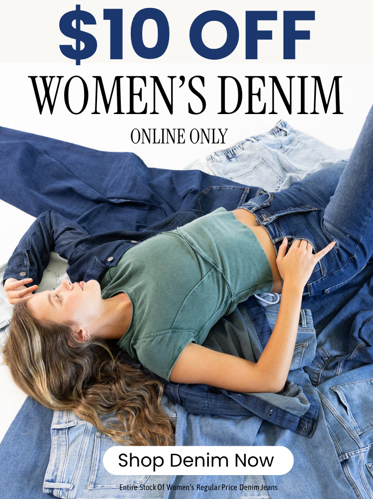 Promotional banner of a woman laying a pile on different washes of denim jeans wearing a green cropped short sleeve t-shirt and one arm in a dark wash denim shirt and dark was jeans.  Text reads $10 OFF WOMEN'S DENIM ONLINE ONLY. A whie call-to-action reads SHOP DENIM NOW. Fine print text reads ENTIRE STOCK OF WOMEN'S REGULAR PRICE DENIM JEANS