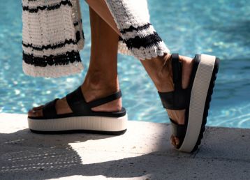 Person walking near water wearing black and white platform sandals and a black and white knit style maxi dress