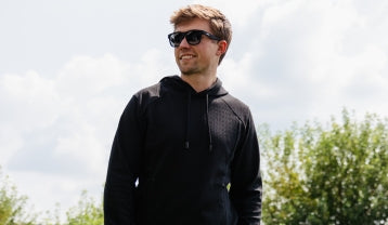 Promotional banner featuring a smiling man wearing black sunglasses and a black hoodie while standing in a sunny outdoor setting