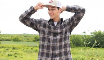 Promotional banner featuring a smiling man wearing a brown and blue plaid button-down shirt and baseball cap while standing in a sunny field.