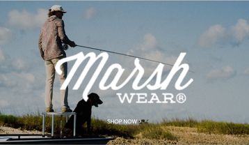 Marsh Wear promotional banner featuring an angler standing on a boat with a fishing rod and a black dog against an open sky and grassy shoreline, with a Shop Now call to action