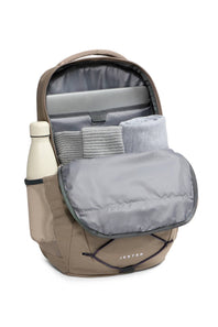 A Jester backpack shown open against a white background, displaying its interior storage compartments, padded zippered pockets, and a side mesh bottle holder with a cream bottle.