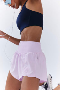 FP Movement Carpe Diem Shorts for Women in Powder Pink; Person wearing a navy top and light purple shorts on a white background