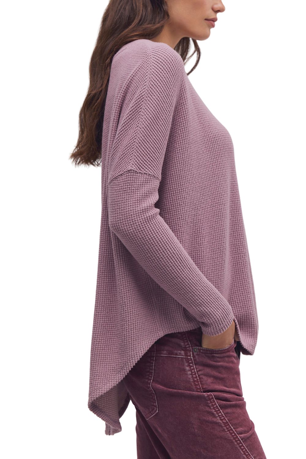 A woman shown from the side wearing a dusty mauve waffle-knit long-sleeve top and dark mauve corduroy pants against a plain white background.