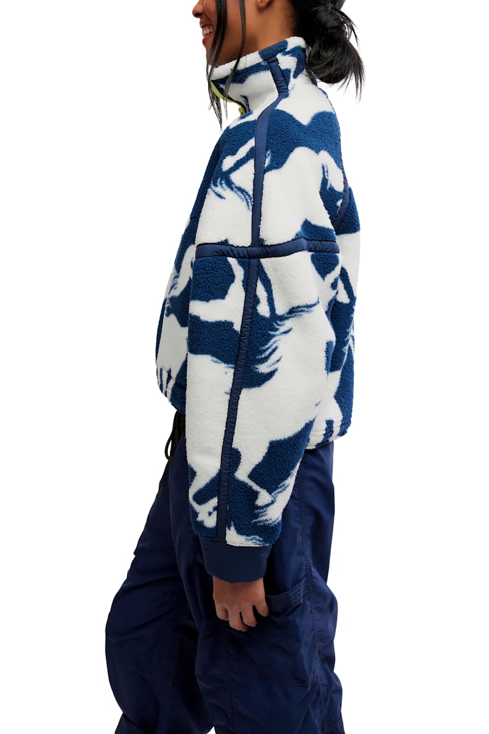 Side profile view showing the sleeve pattern, high collar, and boxy fit of the FP Movement Printed Mountain High 1/2 Zip Fleece in navy and white wild horse print, styled with navy cargo track pants.