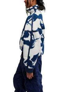 Side profile view showing the sleeve pattern, high collar, and boxy fit of the FP Movement Printed Mountain High 1/2 Zip Fleece in navy and white wild horse print, styled with navy cargo track pants.