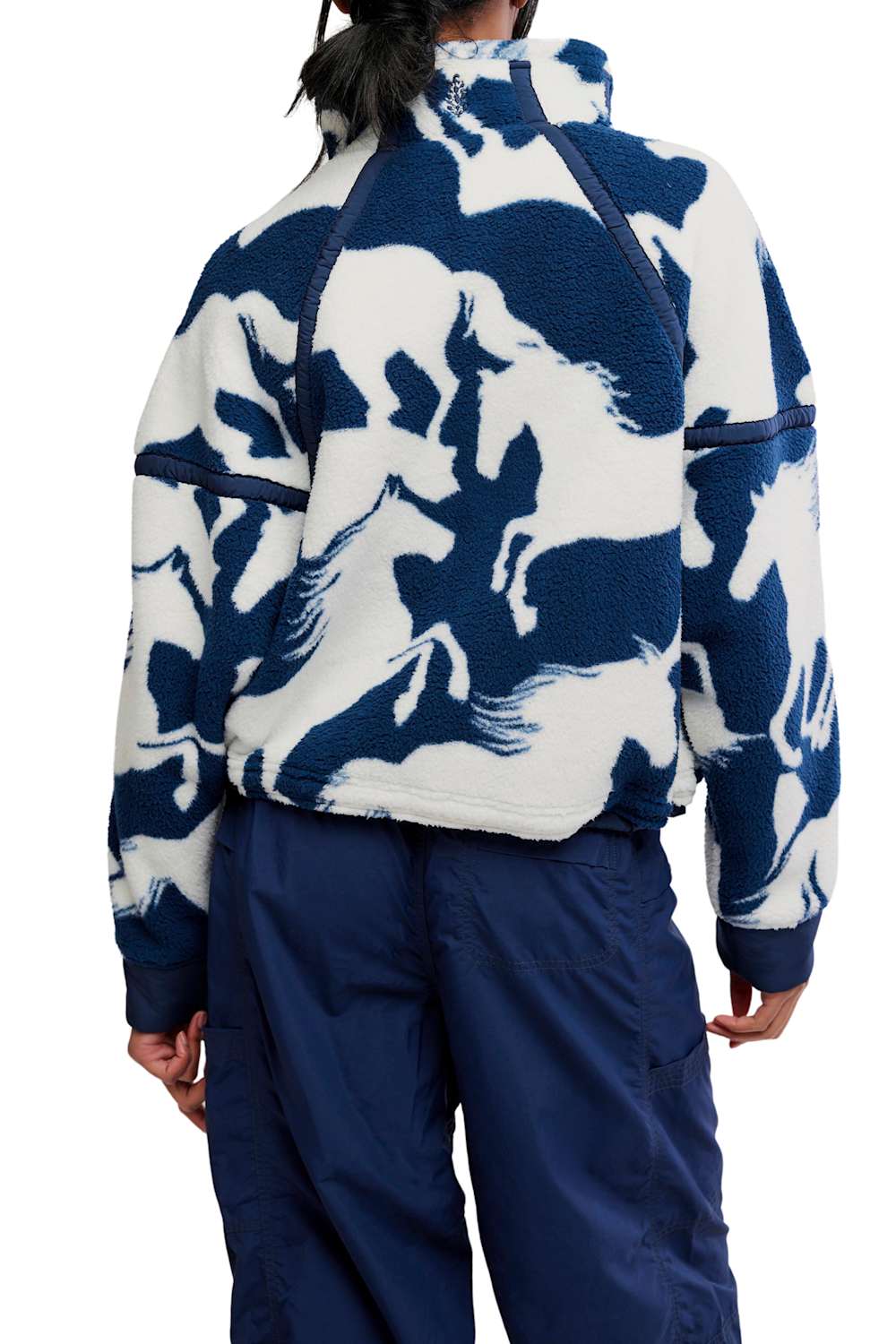 Back view showing the fit and pattern of the FP Movement Printed Mountain High 1/2 Zip Fleece in navy and white wild horse print, featuring drop shoulders, a high collar, and navy ribbed cuffs and hem, paired with high-waisted navy track pants.