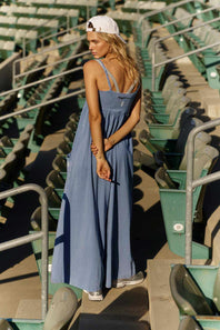 FP Movement Hot Shot Strappy Onesie for Women in Blue Ash; Woman wearing a blue jumpsuit on a white background