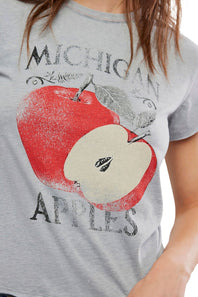 A close-up of a person wearing a heather gray graphic T-shirt featuring a large red apple print with the words 'MICHIGAN APPLES' in distressed black lettering.