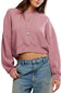 A woman wearing a dusty pink cropped crewneck sweatshirt and blue jeans, shown from the chest down against a plain white background.