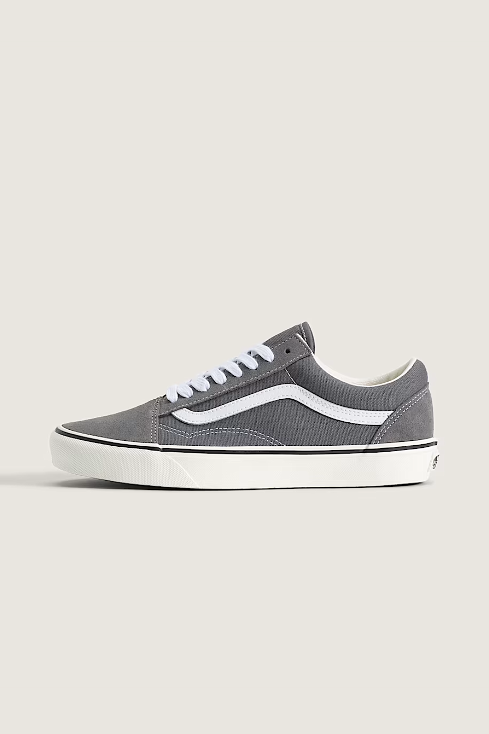 A pair of gray suede Vans Old Skool sneakers with white laces and white side stripes, displayed on a light beige background.