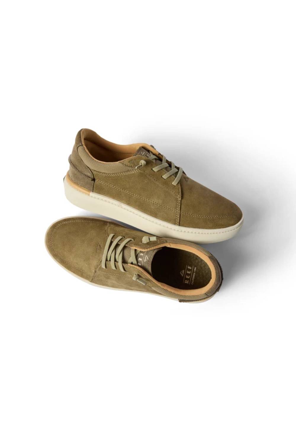 A pair of low-top suede sneakers in a muted olive-tan color, featuring matching laces and thick off-white soles, shown from a top-down angle on a white background.