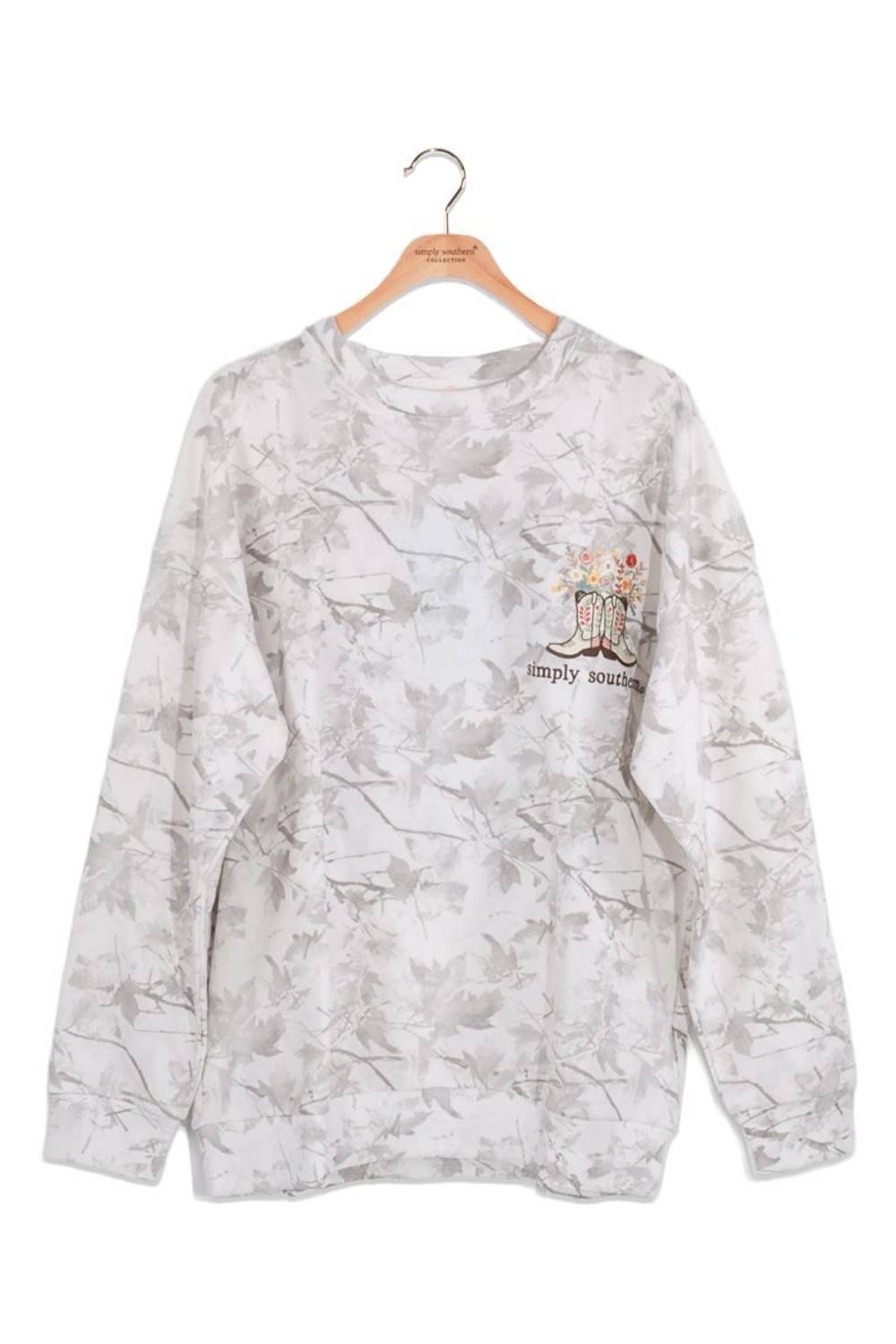 A long-sleeve crewneck sweatshirt with a light gray and white floral pattern, hanging on a wooden hanger. It features a small chest graphic with a pair of boots and the text 'simply southern'.