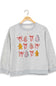 A light gray heather crewneck sweatshirt hanging on a wooden hanger, featuring a festive Christmas graphic print with red bows, gingerbread men, and decorated trees.