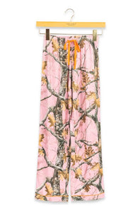 Pink camouflage wide-leg pants with an orange drawstring, hanging from a wooden hanger against a white background.