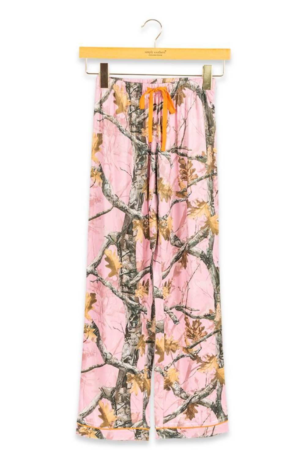 Pink camouflage wide-leg pants with an orange drawstring, hanging from a wooden hanger against a white background.