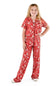 A young girl modeling a red short-sleeve pajama set with a white Christmas tree and deer pattern, standing against a plain white background.