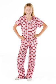 A young girl modeling a two-piece pajama set featuring a pink and red floral pattern, standing against a solid white background.