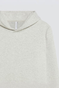 Close-up of a light heather gray hooded sweatshirt, showing the soft knit texture, hood edge, and a small interior neck label.