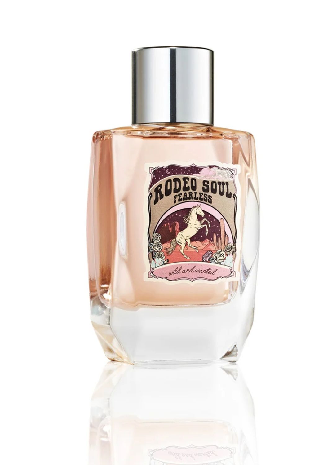 A bottle of Rodeo Soul Fearless perfume with a silver cap and a pinkish-amber liquid inside a clear glass bottle, set against a white background with a soft reflection.