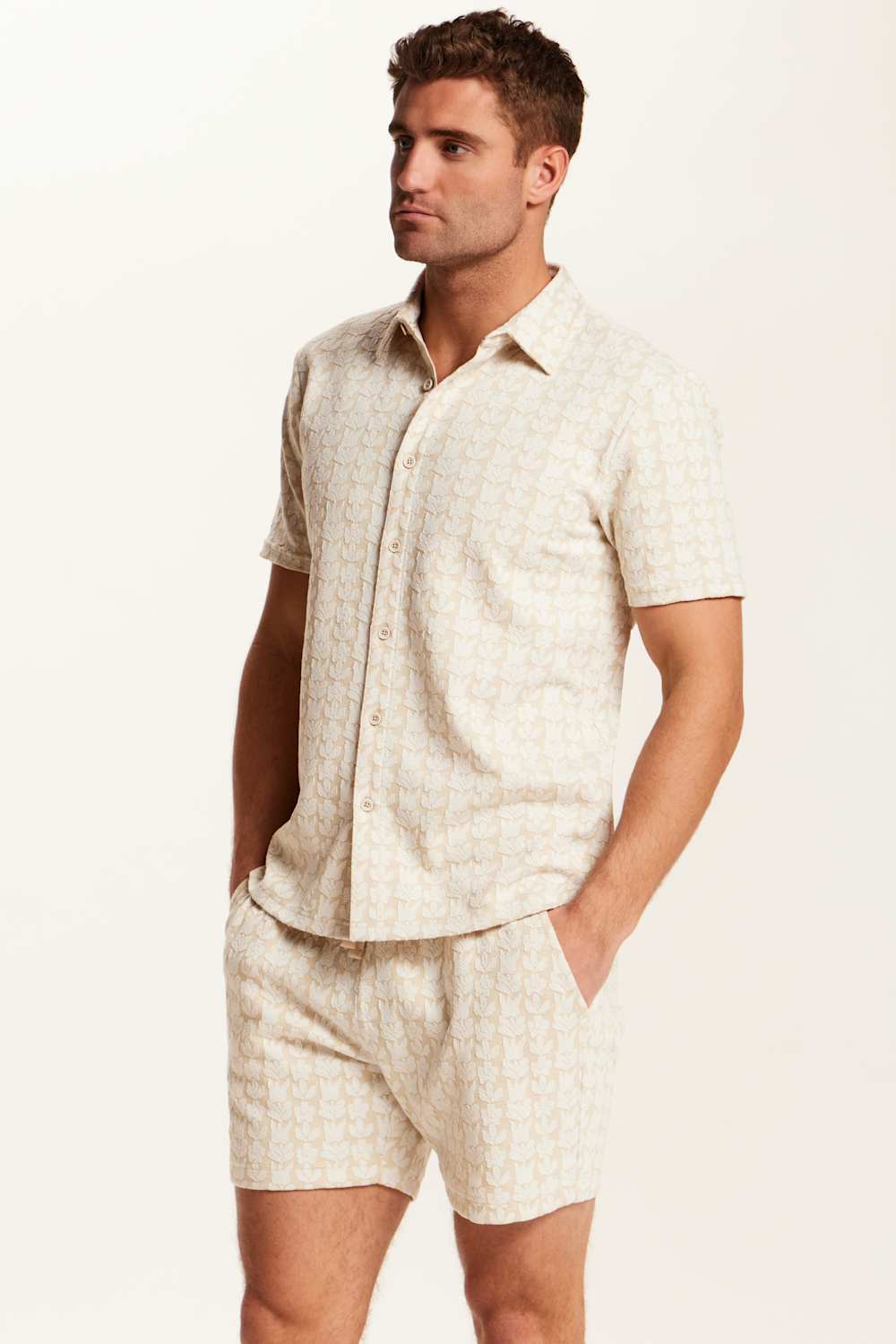 Weatherproof Vintage Knit Jacquard Coatfront Shirt for Men in Cream; Man wearing a beige patterned shirt and shorts on a white background