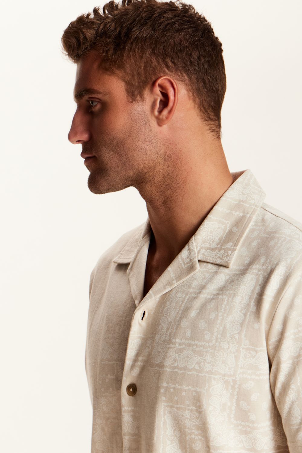 Weatherproof Vintage Bandana Camp Shirt for Men in Tan; Man wearing a beige linen shirt against a plain background