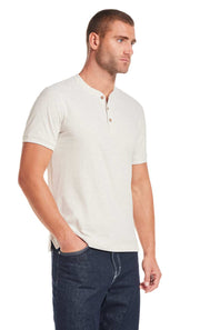 Weatherproof Vintage Jersey Henley Shirt for Men in OatmealMan wearing a beige short-sleeve henley shirt and dark jeans on a white background 