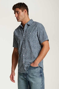 Weatherproof Vintage Poplin Button Up Shirt for Men in Teal; Man wearing a short-sleeve patterned shirt and jeans on a plain background