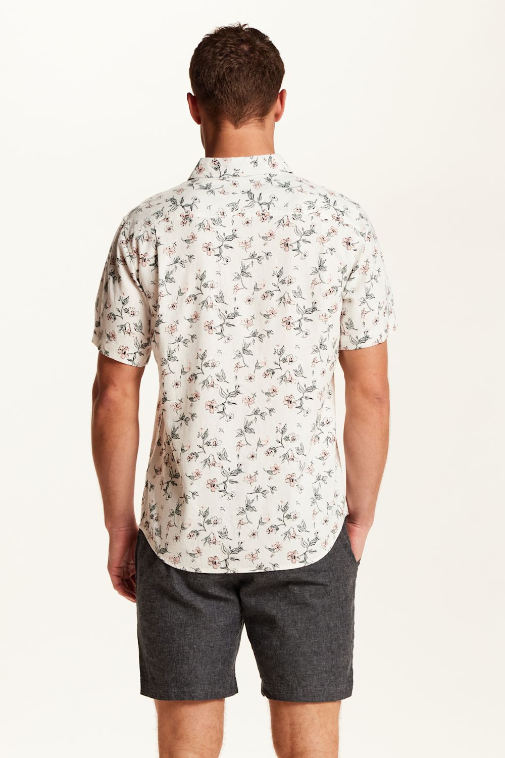 Weatherproof Vintage Linen Rayon Printed Shirt for Men in Cloud Pink; Man wearing a floral short-sleeve shirt and dark shorts on a white background