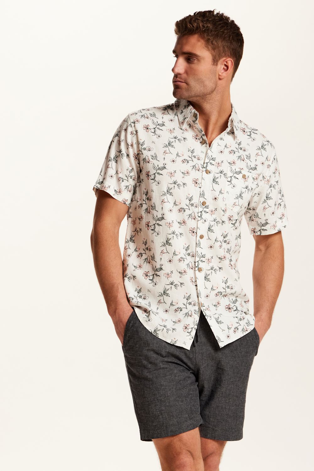 Weatherproof Vintage Linen Rayon Printed Shirt for Men in Cloud Pink; Man wearing a floral short-sleeve shirt and dark shorts on a white background