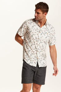 Weatherproof Vintage Linen Rayon Printed Shirt for Men in Cloud Pink; Man wearing a floral short-sleeve shirt and dark shorts on a white background