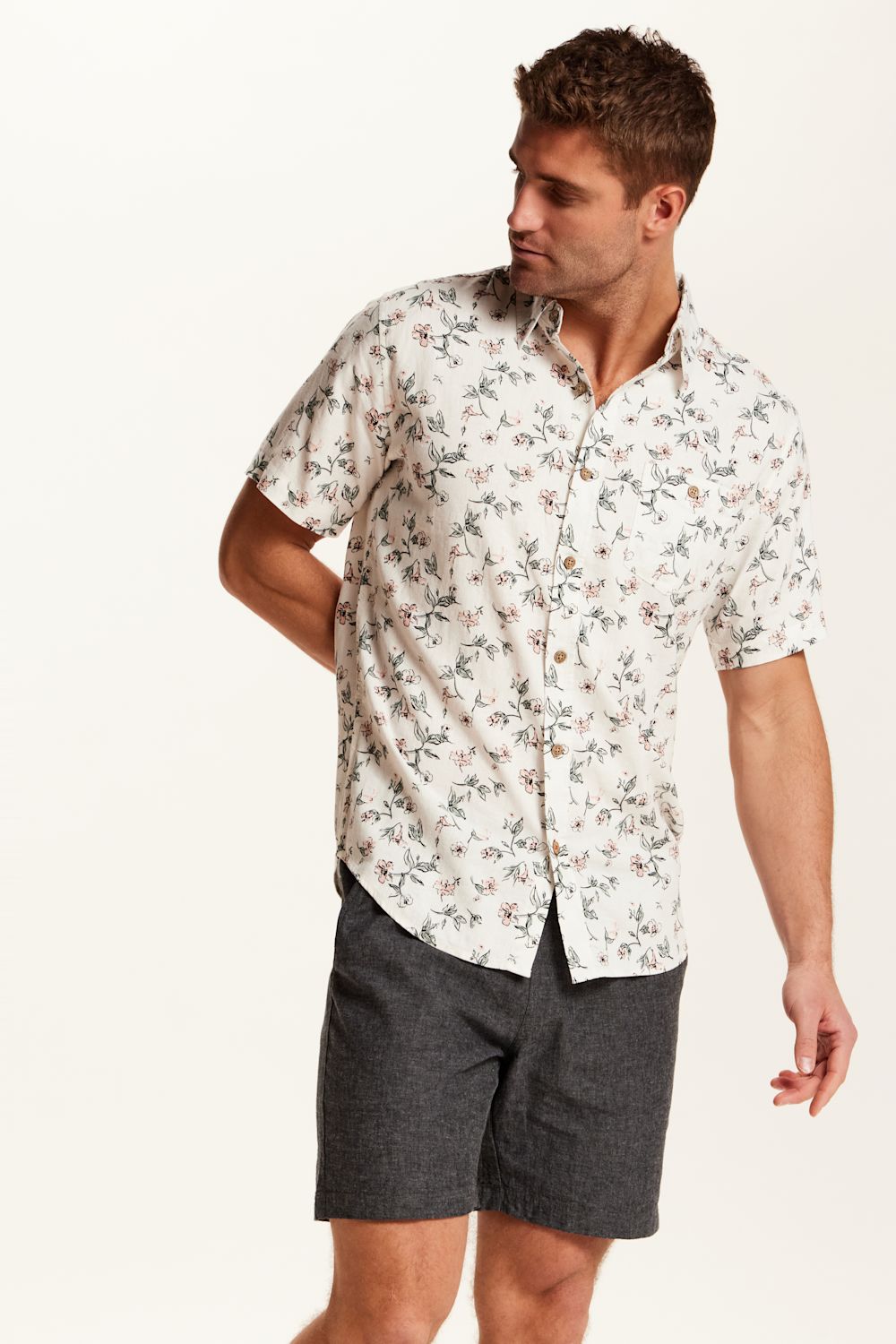 Weatherproof Vintage Linen Rayon Printed Shirt for Men in Cloud Pink; Man wearing a floral short-sleeve shirt and dark shorts on a white background
