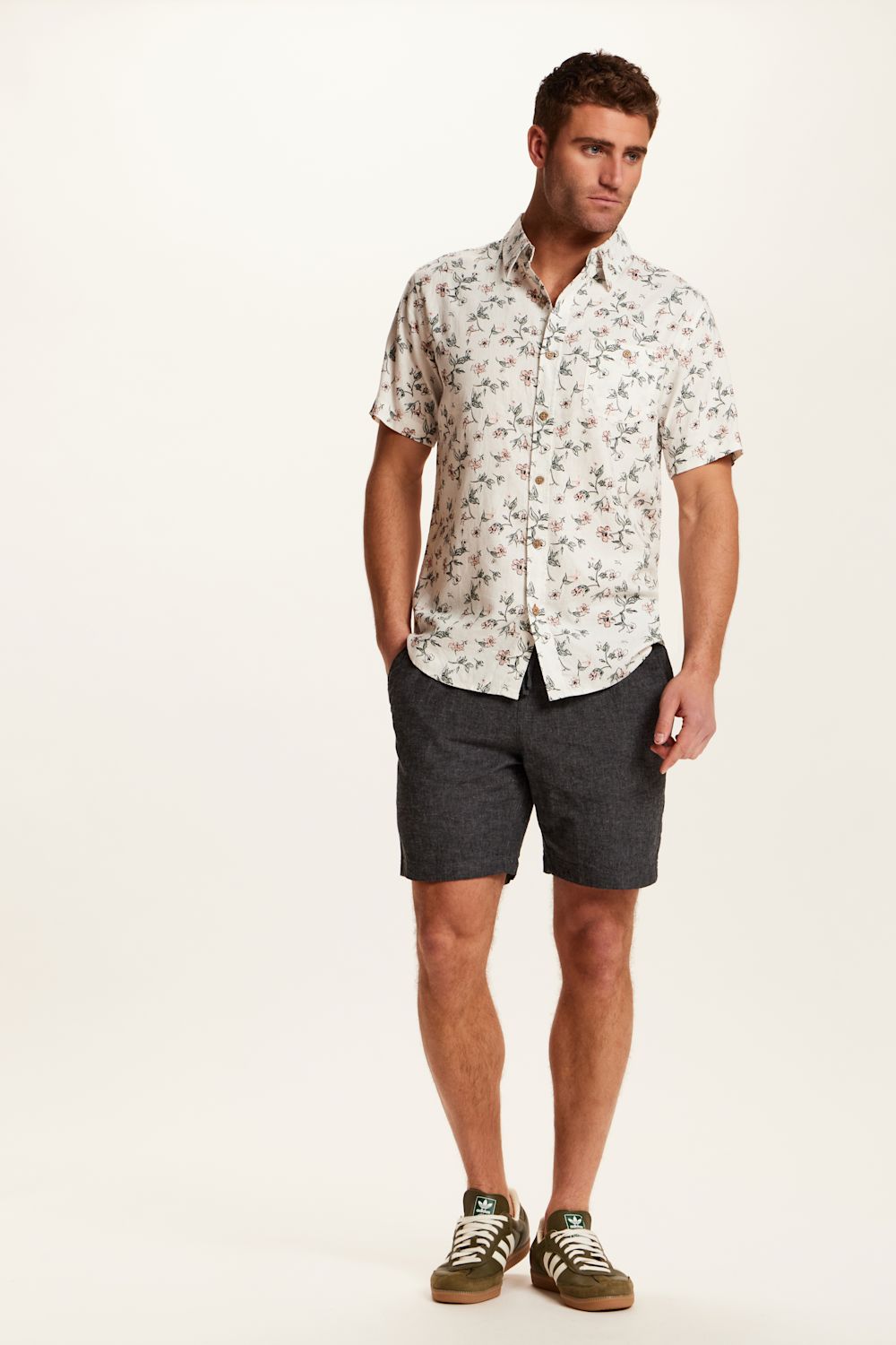 Weatherproof Vintage Linen Rayon Printed Shirt for Men in Cloud Pink; Man wearing a floral shirt and dark shorts on a white background