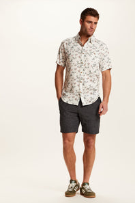 Weatherproof Vintage Linen Rayon Printed Shirt for Men in Cloud Pink; Man wearing a floral shirt and dark shorts on a white background