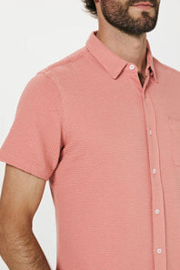 Man wearing a pink short-sleeve shirt against a white background