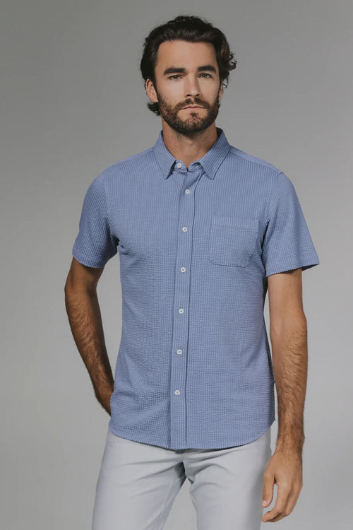 Man wearing a blue checkered shirt against a gray background