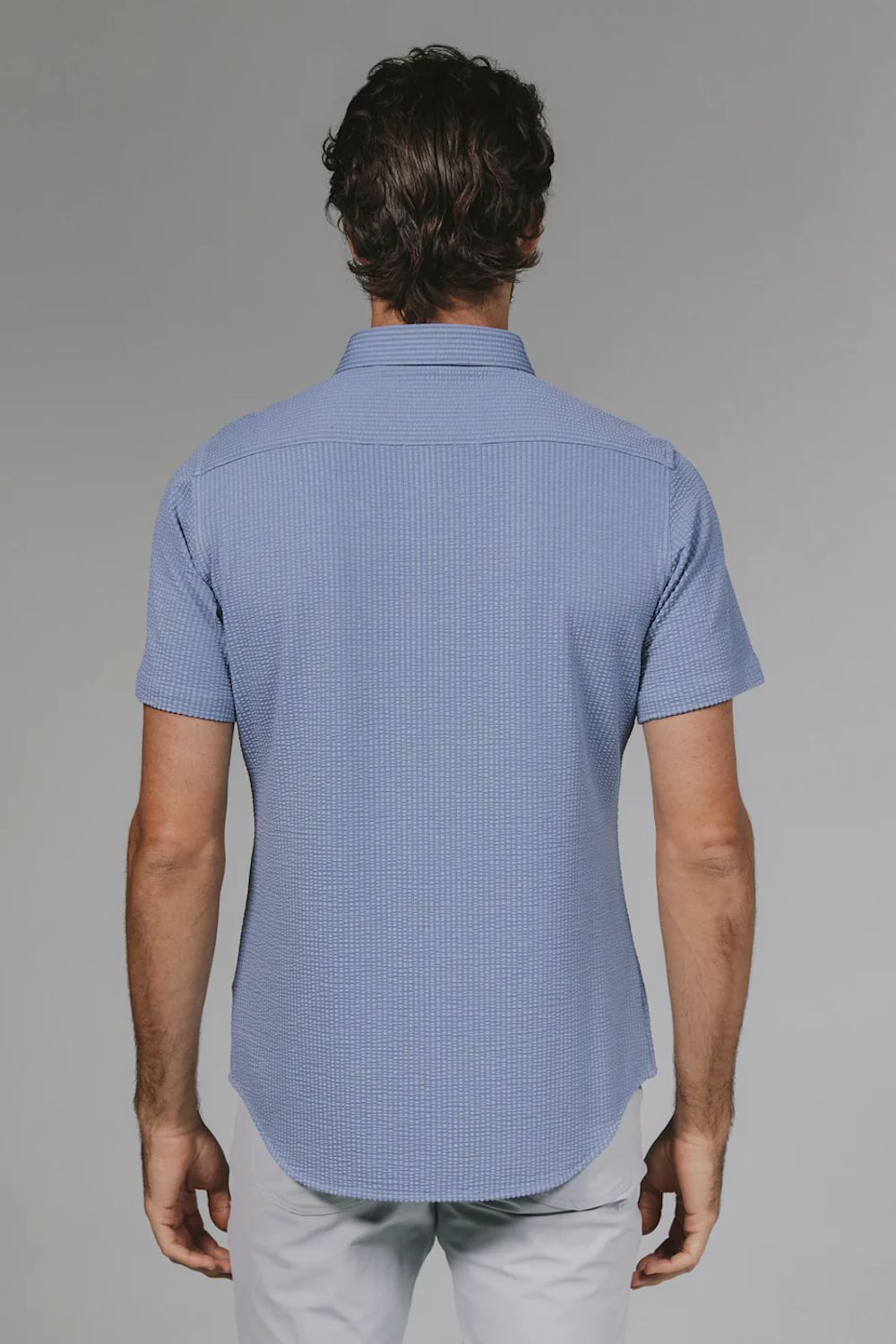 Man wearing a blue checkered shirt against a gray background