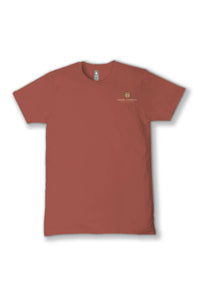A short-sleeve crewneck t-shirt in a muted terracotta or rust color, featuring a small gold embroidered crest and the words 'simply southern' on the left chest, displayed against a clean white background.