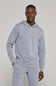 A man wearing a matching light periwinkle blue hoodie and sweatpants set, standing against a neutral light gray studio background.
