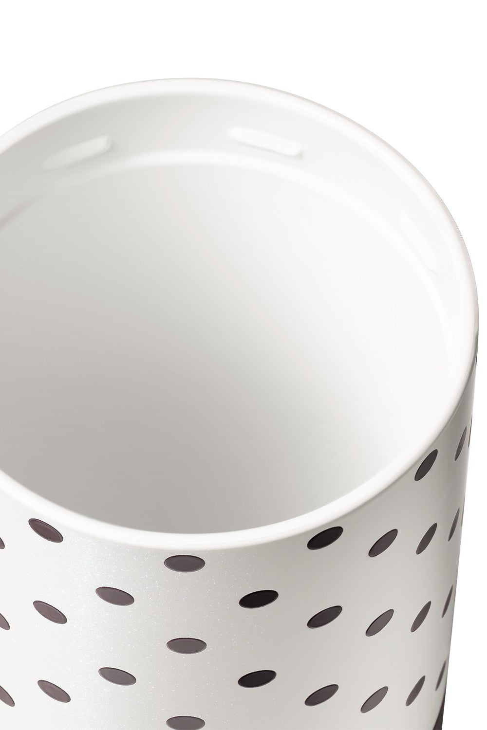 A close-up of a white cylindrical container or cup with a black polka dot pattern on the exterior, photographed against a white background.