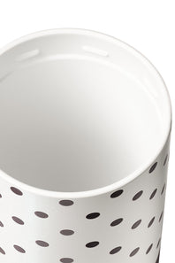 A close-up of a white cylindrical container or cup with a black polka dot pattern on the exterior, photographed against a white background.