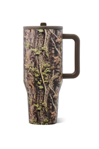 A travel tumbler with a woodland camouflage pattern featuring brown branches, green leaves, and beige bark, with a dark brown handle and lid, shown on a white background.