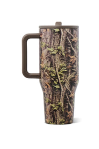 A travel tumbler with a woodland camouflage pattern featuring tree bark, leaves, and vines, complete with a brown handle and lid, shown on a plain white background.