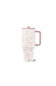 A tall travel mug with a pink handle and lid, featuring a delicate pink and white floral pattern, set against a plain white background.