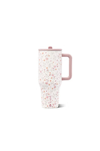 A tall travel mug with a pink handle and lid, featuring a delicate pink and white floral pattern, set against a plain white background.