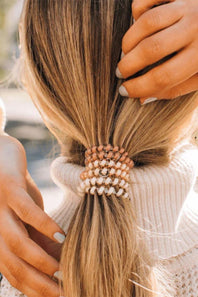 Person styling a ponytail with a decorative hair tie.