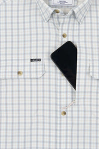 A close-up of a light blue and white checkered button-down shirt with a black smartphone resting in the chest pocket. The brand label 'PONCHO' is visible on the pocket flap.