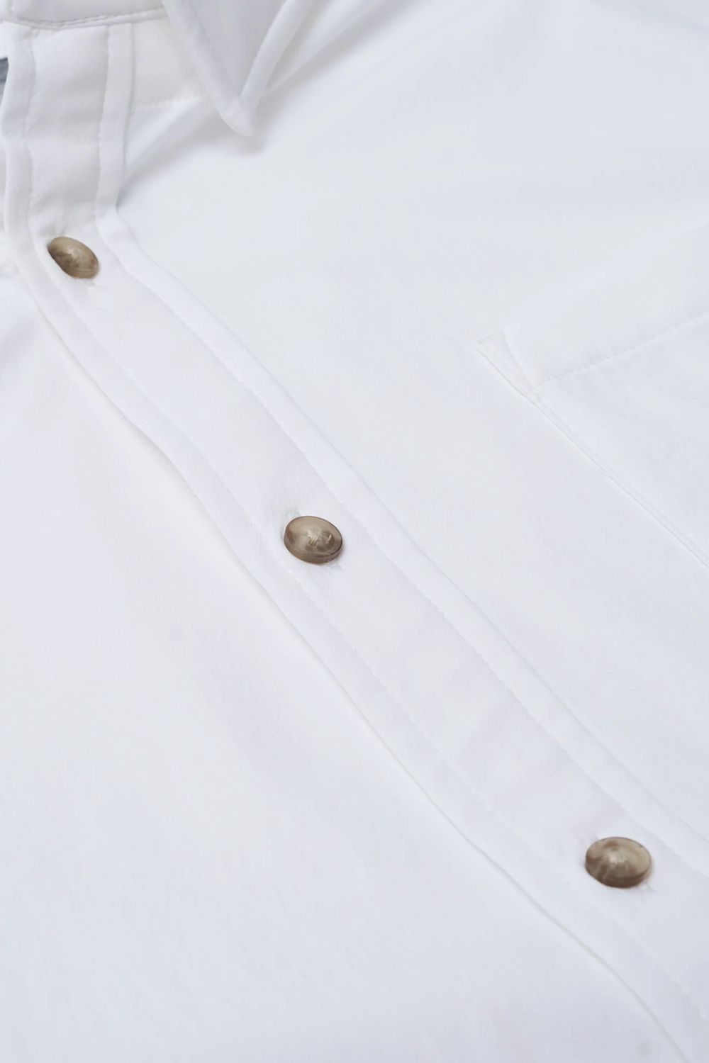 Close-up of a white button-up shirt showing the front placket with metallic brown buttons and part of the collar.