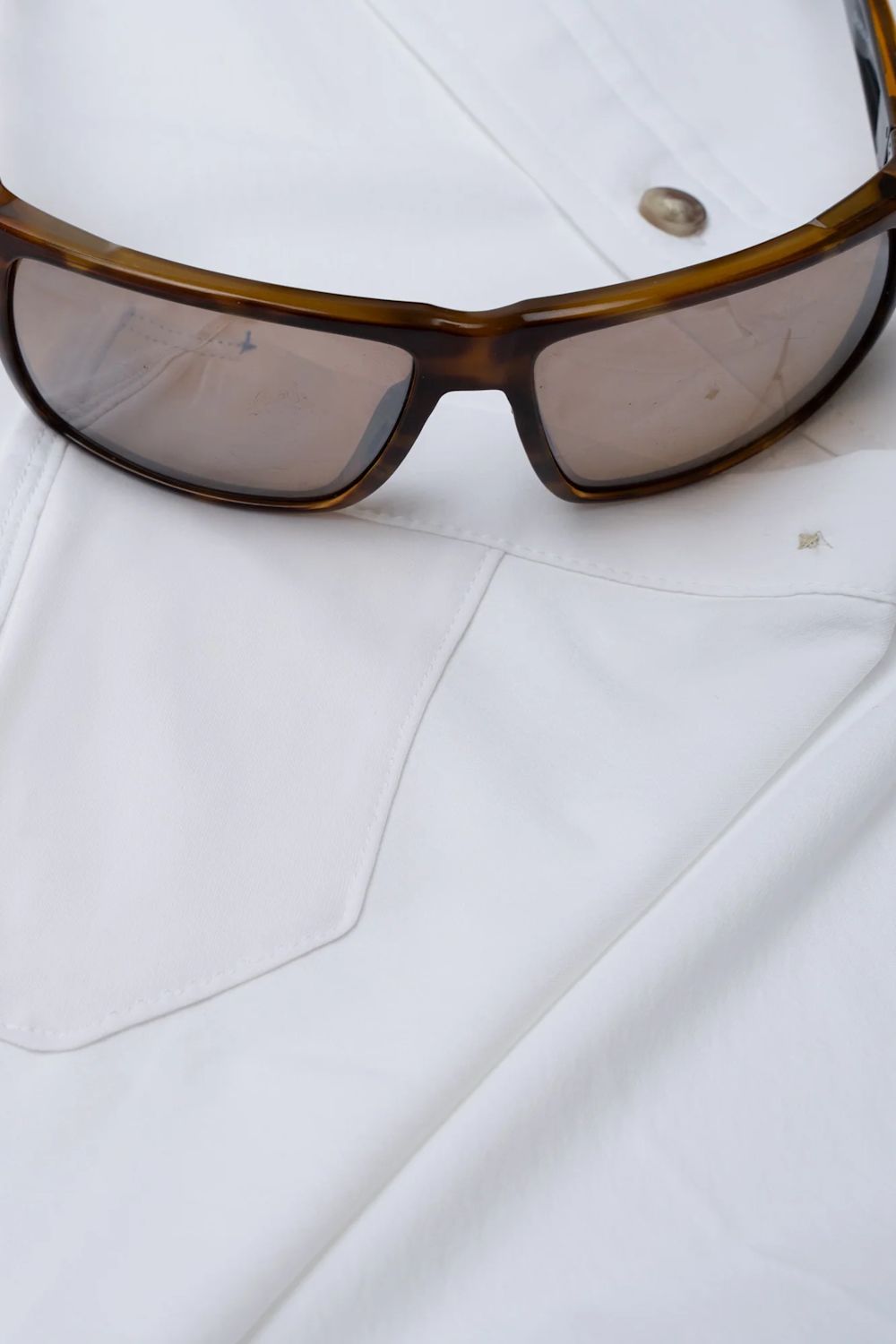 Brown tortoiseshell sunglasses with tinted lenses resting on a white button-down shirt.