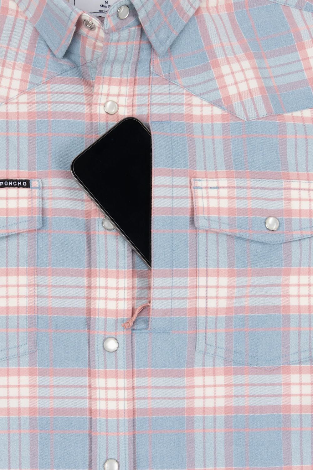 A close-up of a light blue and pink plaid button-down shirt with a black smartphone placed on the chest pocket area.